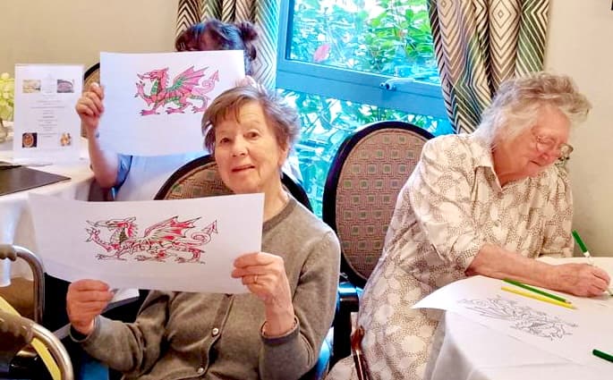 A resident holding a drawing of the welsh dragon at Ty Llandaff Care Home