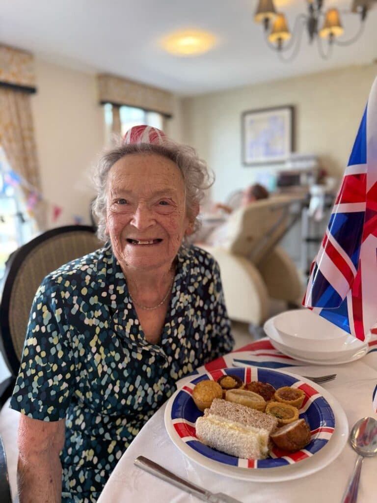 one of our residents sat with their VE day lunch smiling